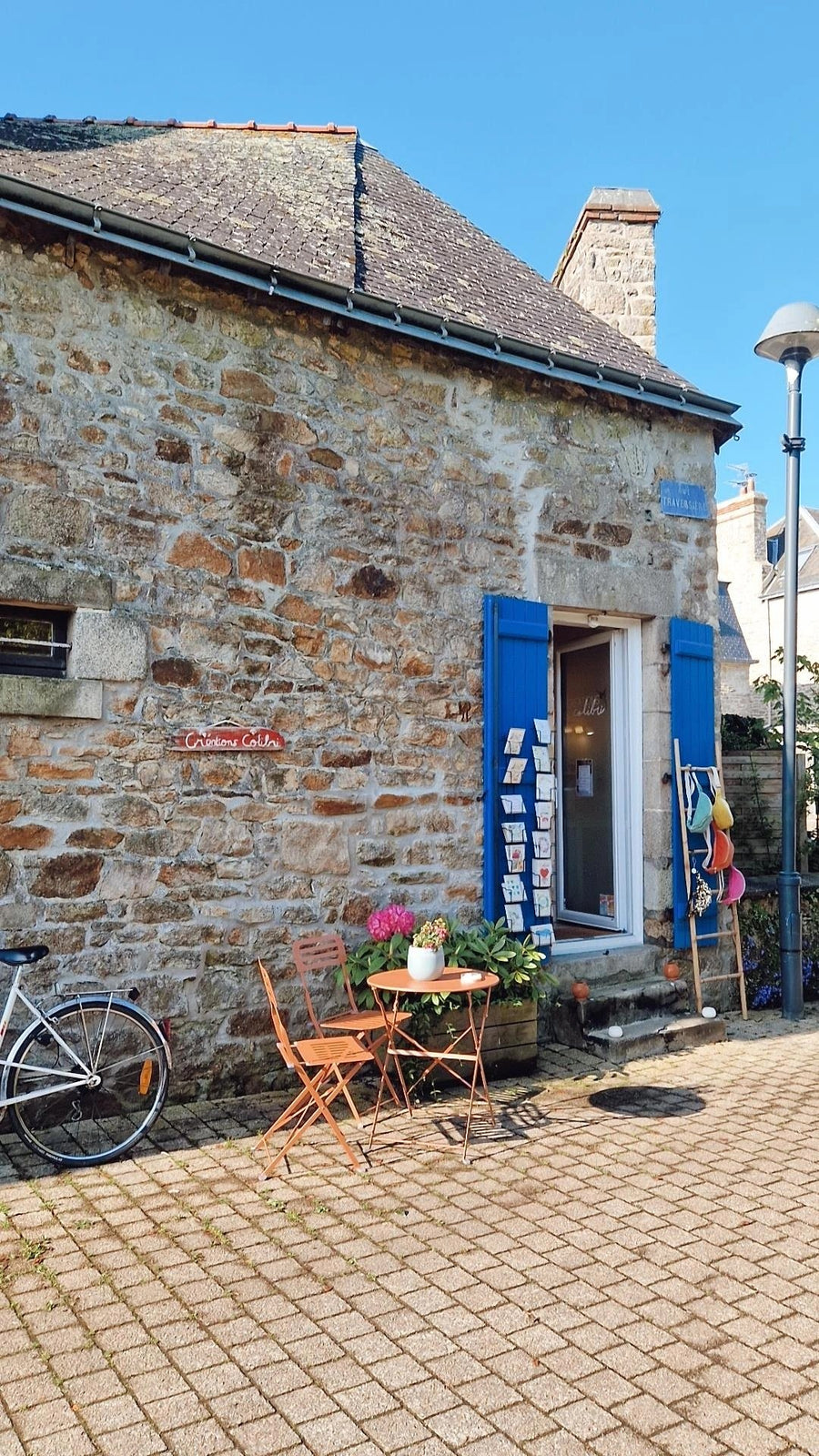 La façade en pierre de l'atelier-boutique Créations Colibri à Plœmeur, volets bleus